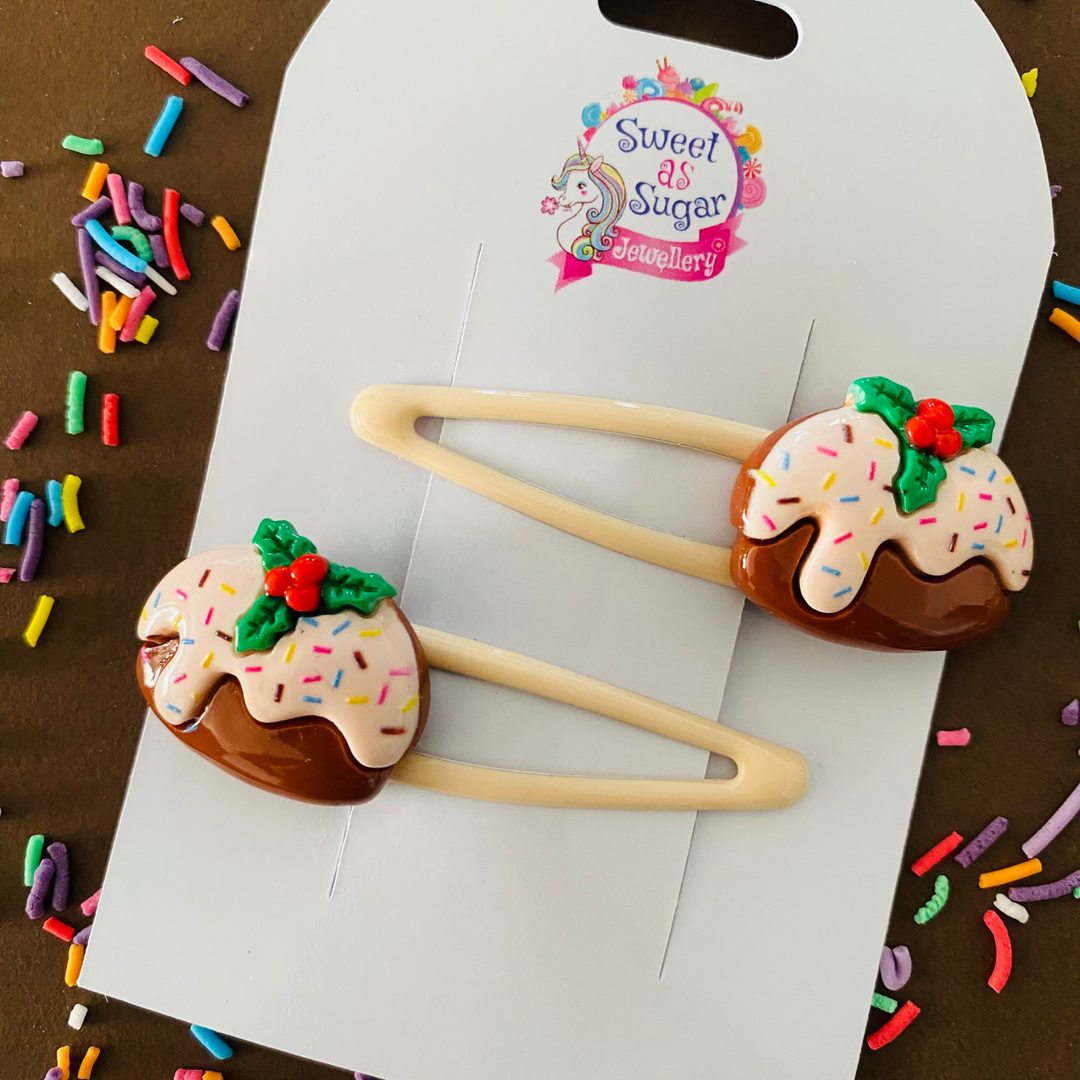 A pair of Christmas pudding charms set on cream hair clips.