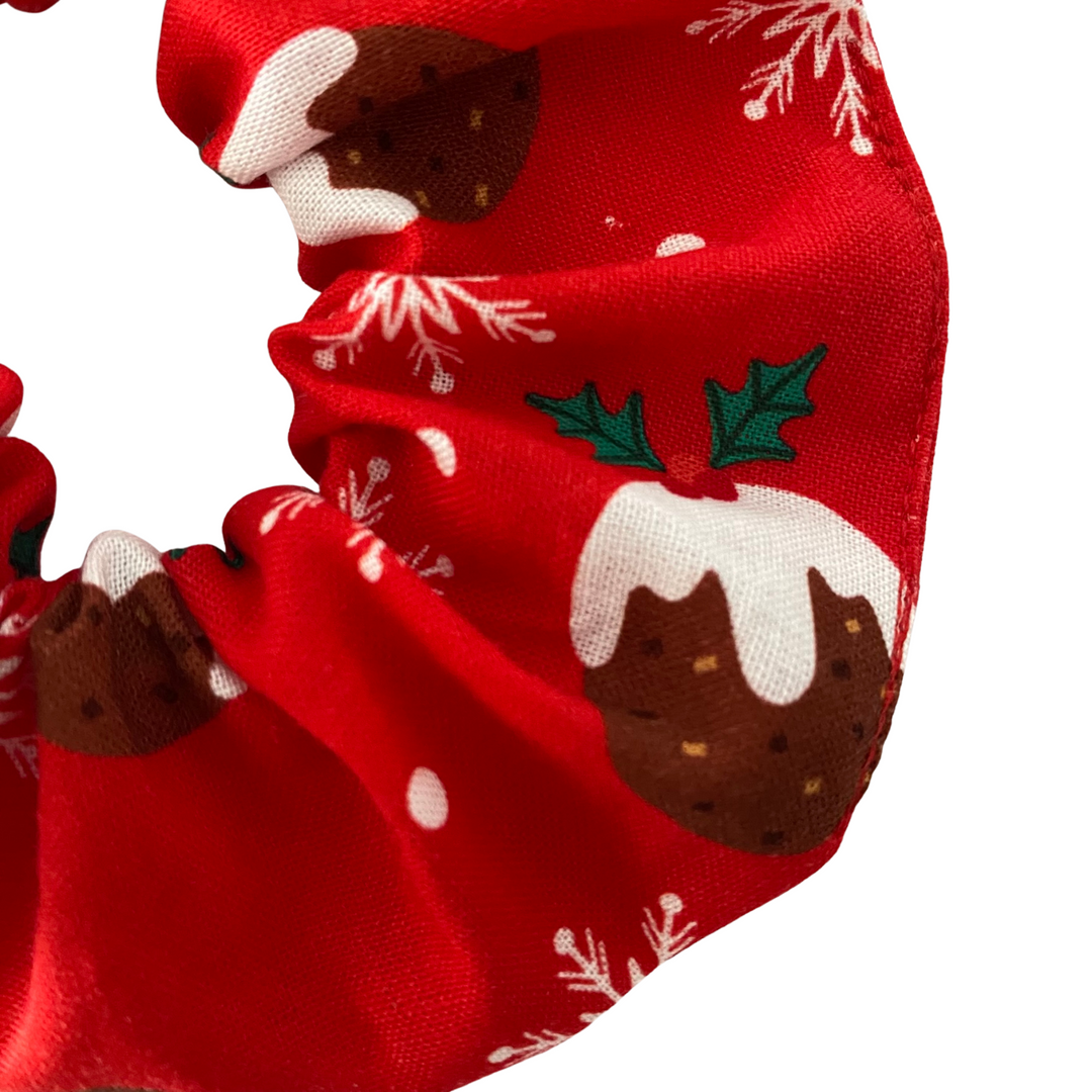 Red Christmas-themed fabric with pudding and holly design on a white background.
