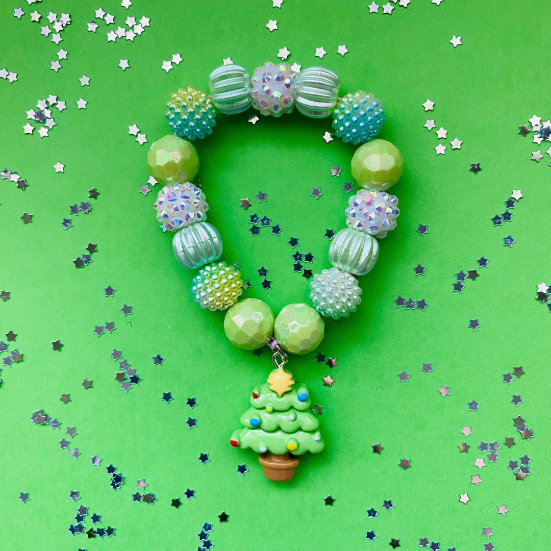A beaded Christmas-themed bracelet with green, blue and iridescent beads, featuring a small green tree charm.