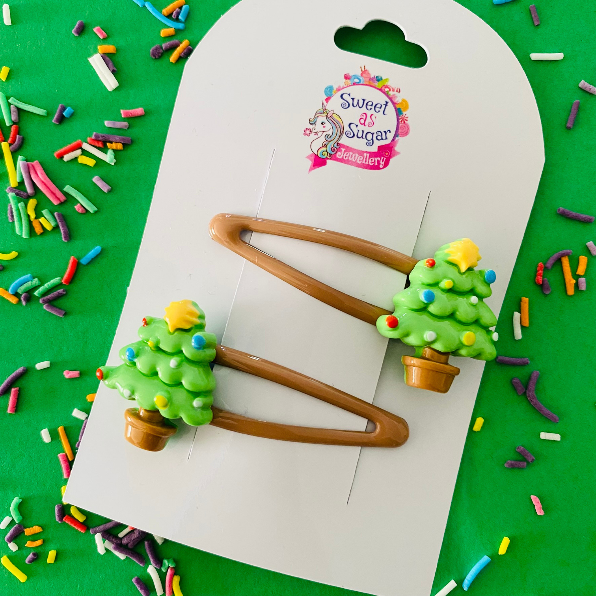 A pair of green Christmas Tree charms set on brown hair clips.
