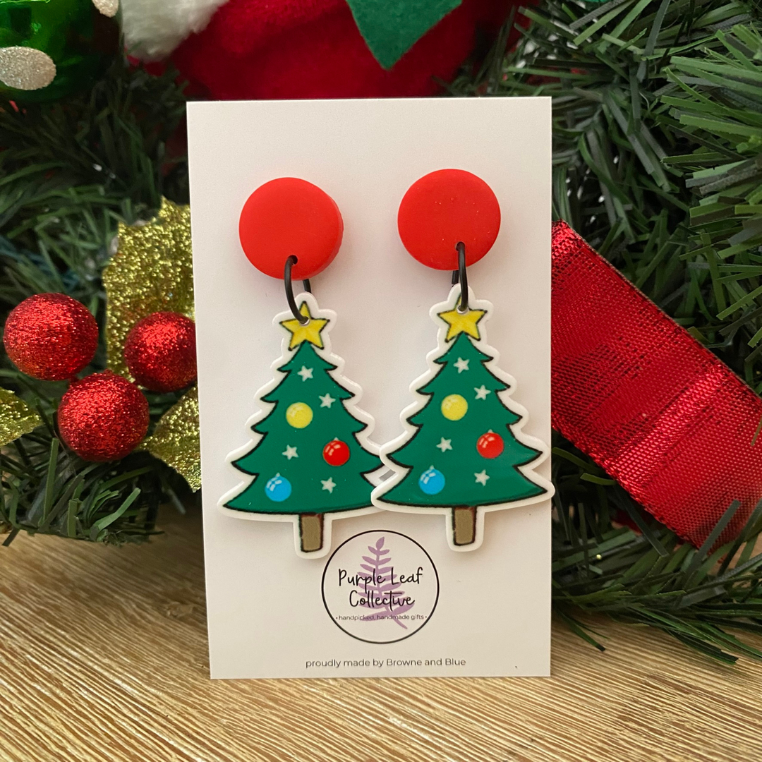 Christmas tree earrings on a card with festive background.