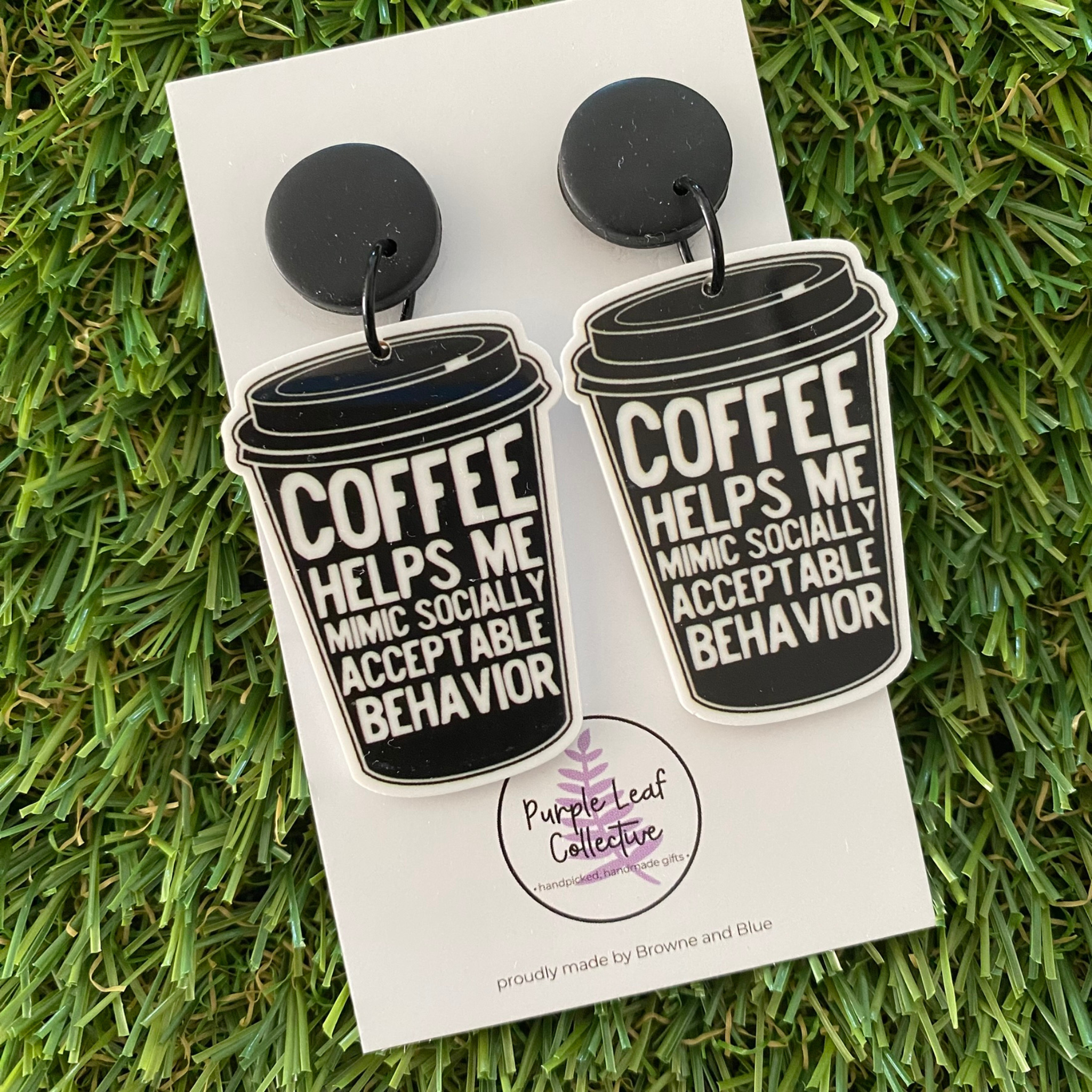 Novelty dangle earrings shaped like black coffee cups with text that reads Coffee Helps Me Mimic Socially Acceptable Behavior set on black stud tops.