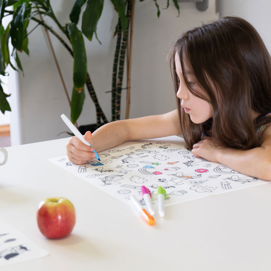 An image of a girl colouring in the Unicorn silicone placemat.