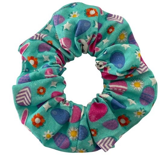 Scrunchie with images of Easter bunnies and patterned Easter eggs on a blue fabric.