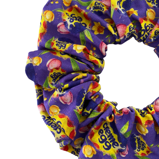 Cadbury Dairy Milk chocolate images on a purple scrunchie.