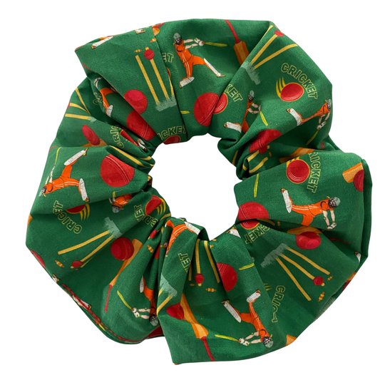Green scrunchie with cricket-themed design featuring a pattern of female cricket players, bats, balls and stumps.