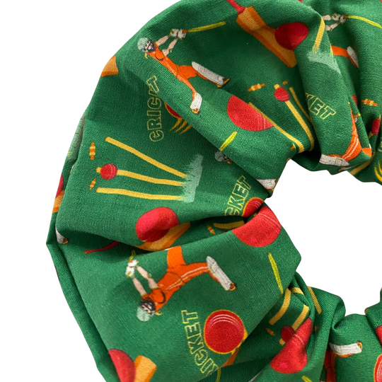 Green scrunchie with cricket-themed design on a white background.