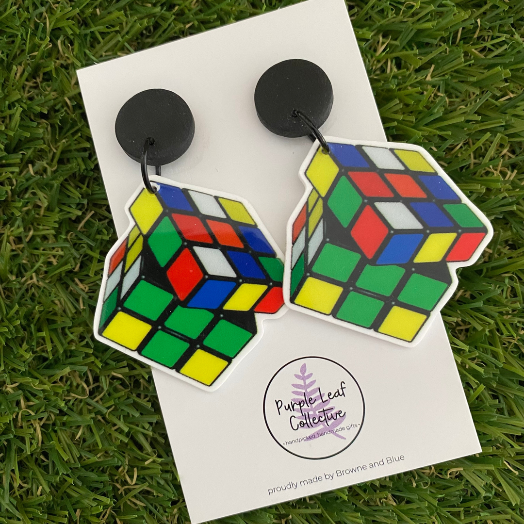 Rubik's Cube-shaped dangle earrings with black stud tops on a white backing card.