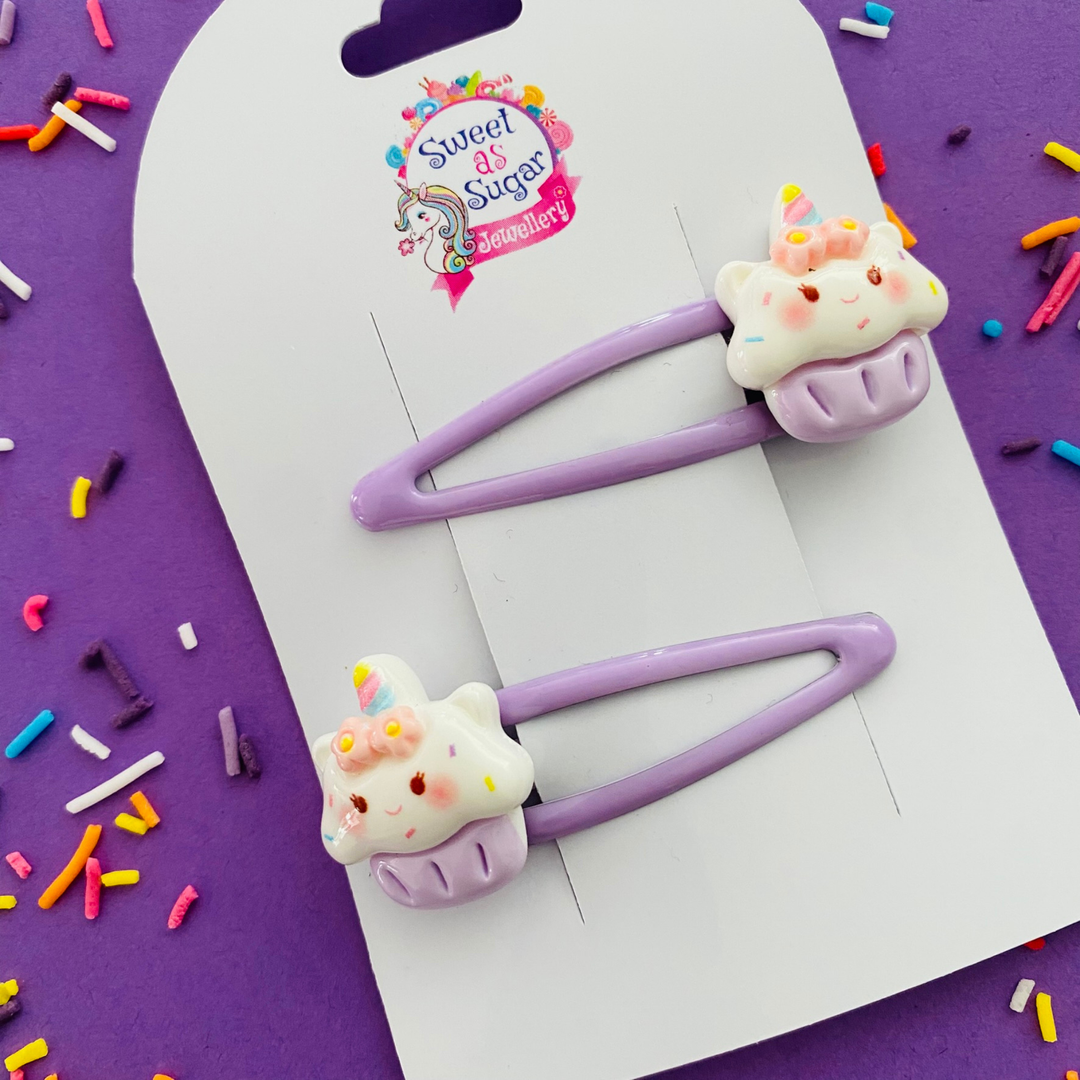 A pair of lavender snap clips featuring a cupcake sitting in a lavender base.