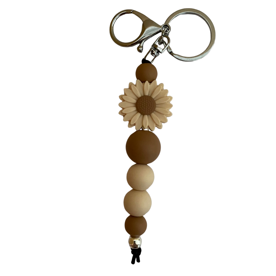 A keyring with a daisy cream silicone bead and other assorted beads.