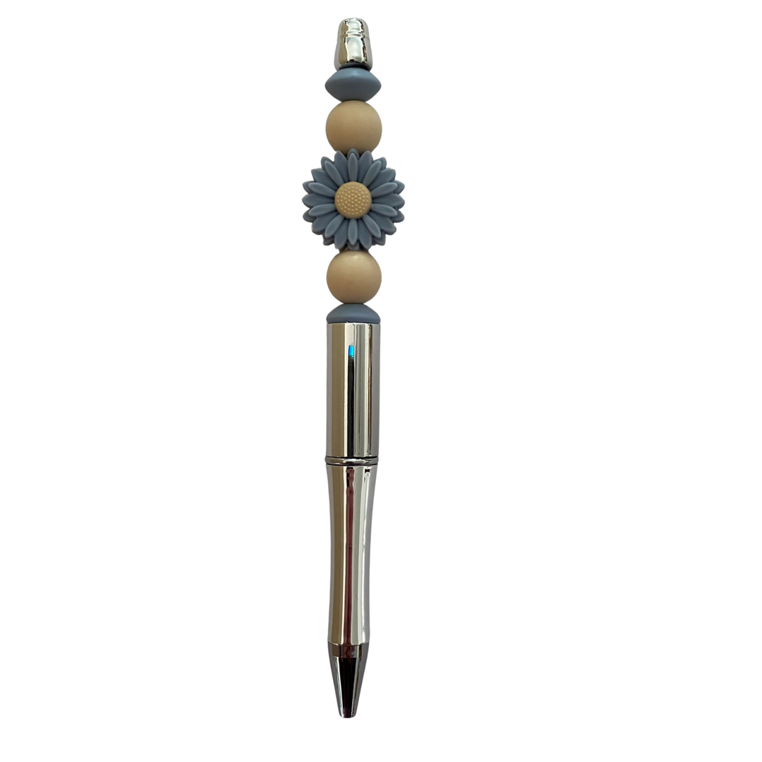 Decorative pen with beads and a dusky blue flower design on a white background.