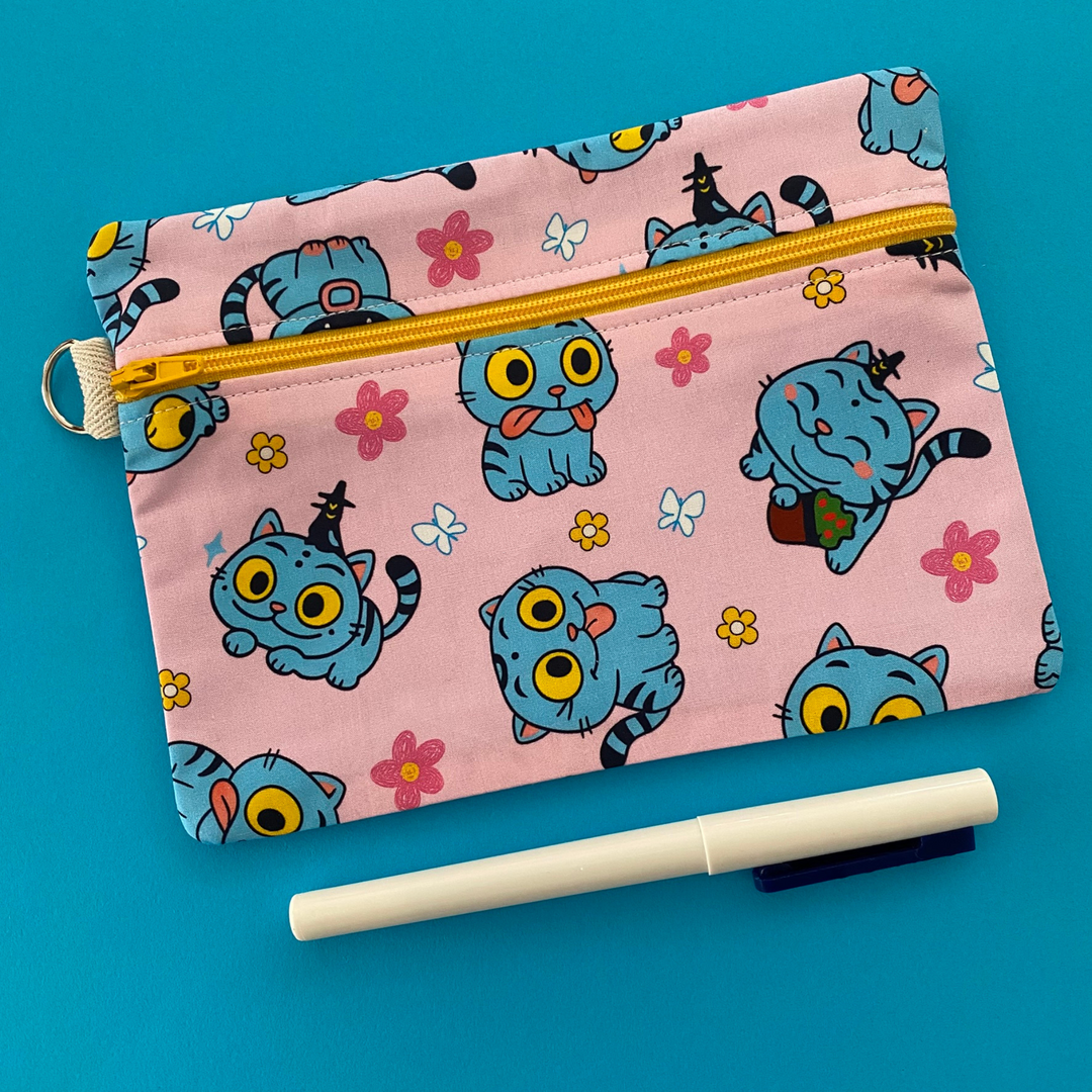 Pink pouch with blue cat pattern on a blue background.