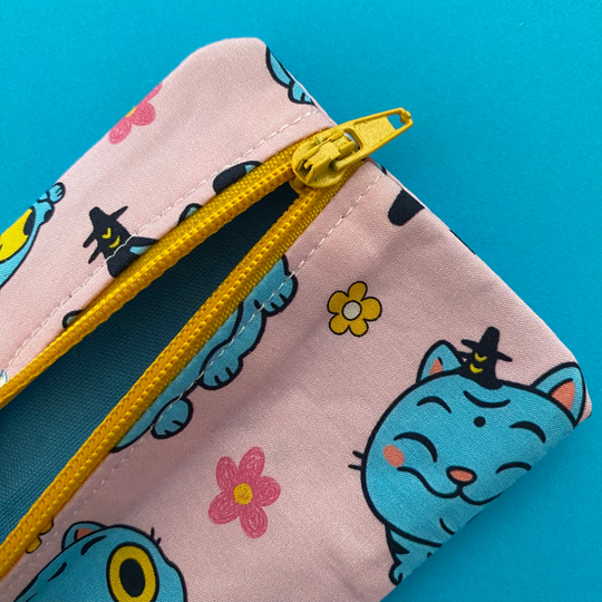 Side view showing lining of Derpy Tiger from K-Pop Demon Hunters featured on a light pink coin purse with clasp.