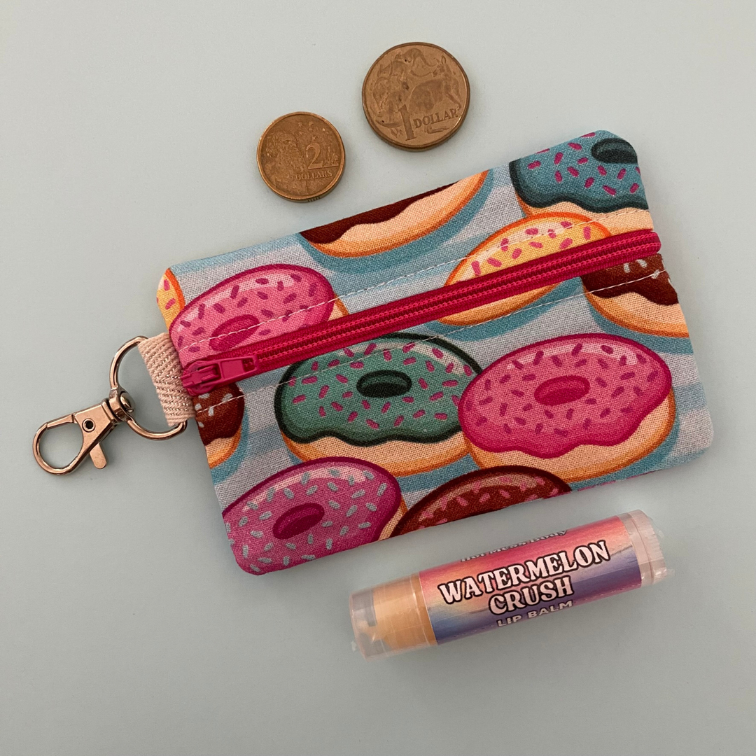 A small clip coin purse perfect for coins and small essentials featuring colourful, mouth-watering donut illustrations.
