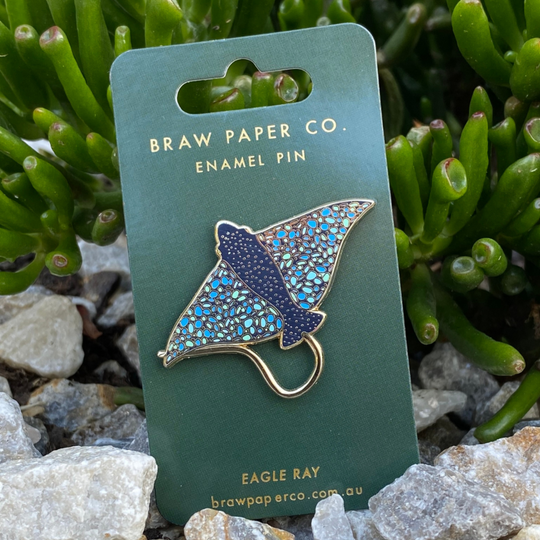 The Eagle Ray Enamel Pin showcases a stunning and graceful Eagle Ray, capturing the light and shimmering with elegance.