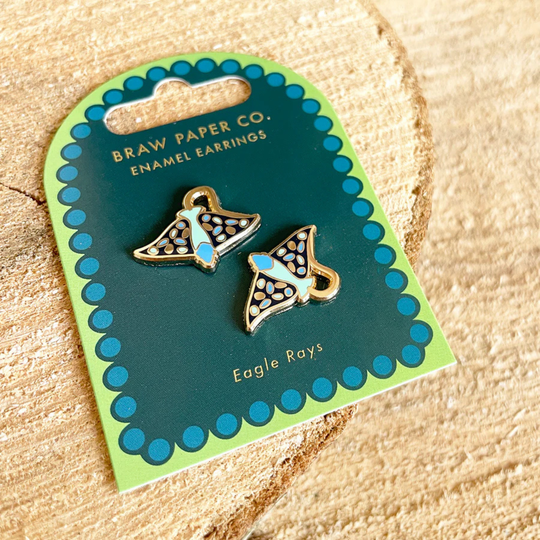 Enamel earrings of eagle rays on a Braw Paper Co. card against a beige background.