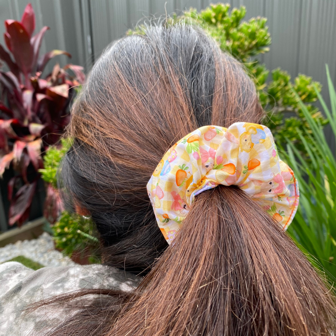 Person with a Easter pattern scrunchie in their hair, surrounded by plants.