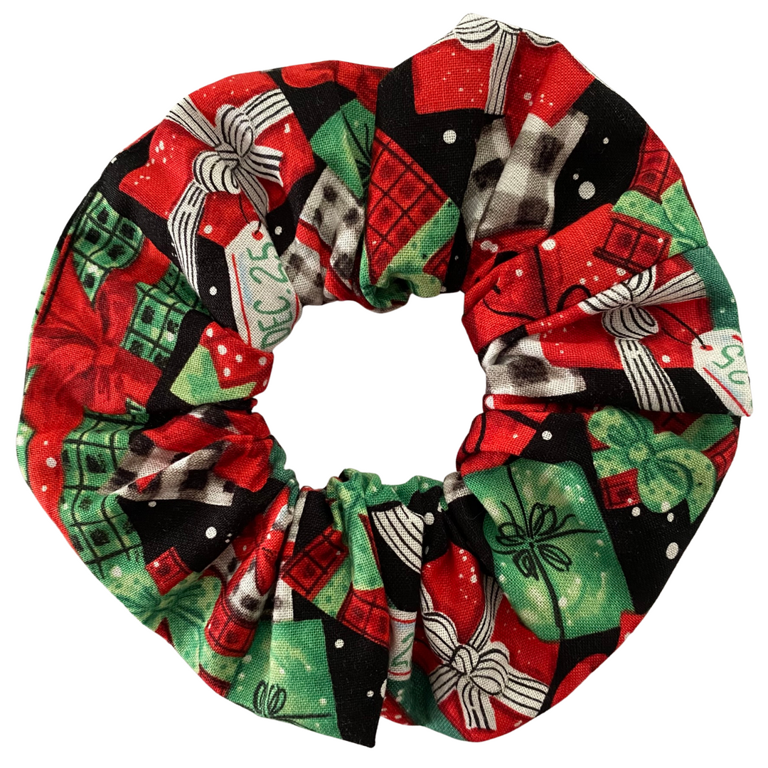 Christmas red and green gifts on a black fabric scrunchie on a white background.