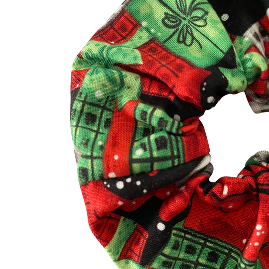 Close up view of a Christmas red and green gifts on a black fabric scrunchie on a white background.