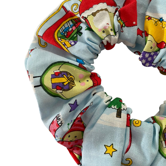 A scrunchie featuring playful festive Christmas avocados on a light blue fabric.
