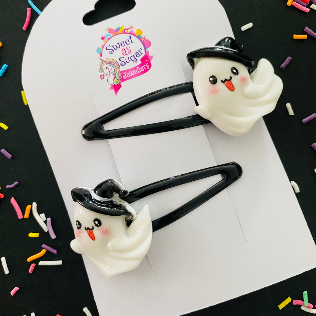 A pair of black hair clips with a ghost wearing a witch hat charm.