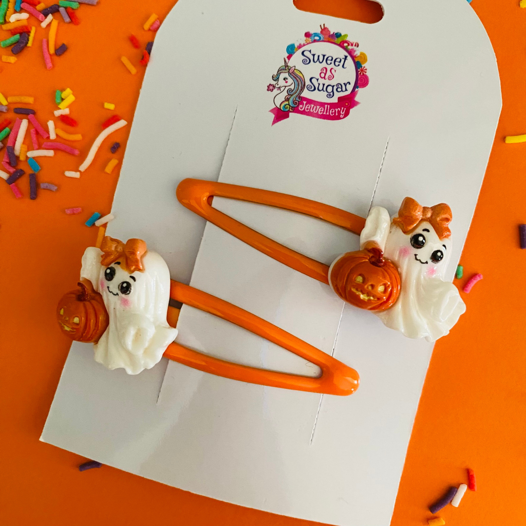 Ghost hair clips feature a white ghost adorned with a matching orange bow and a pumpkin, all set on orange hair clip.