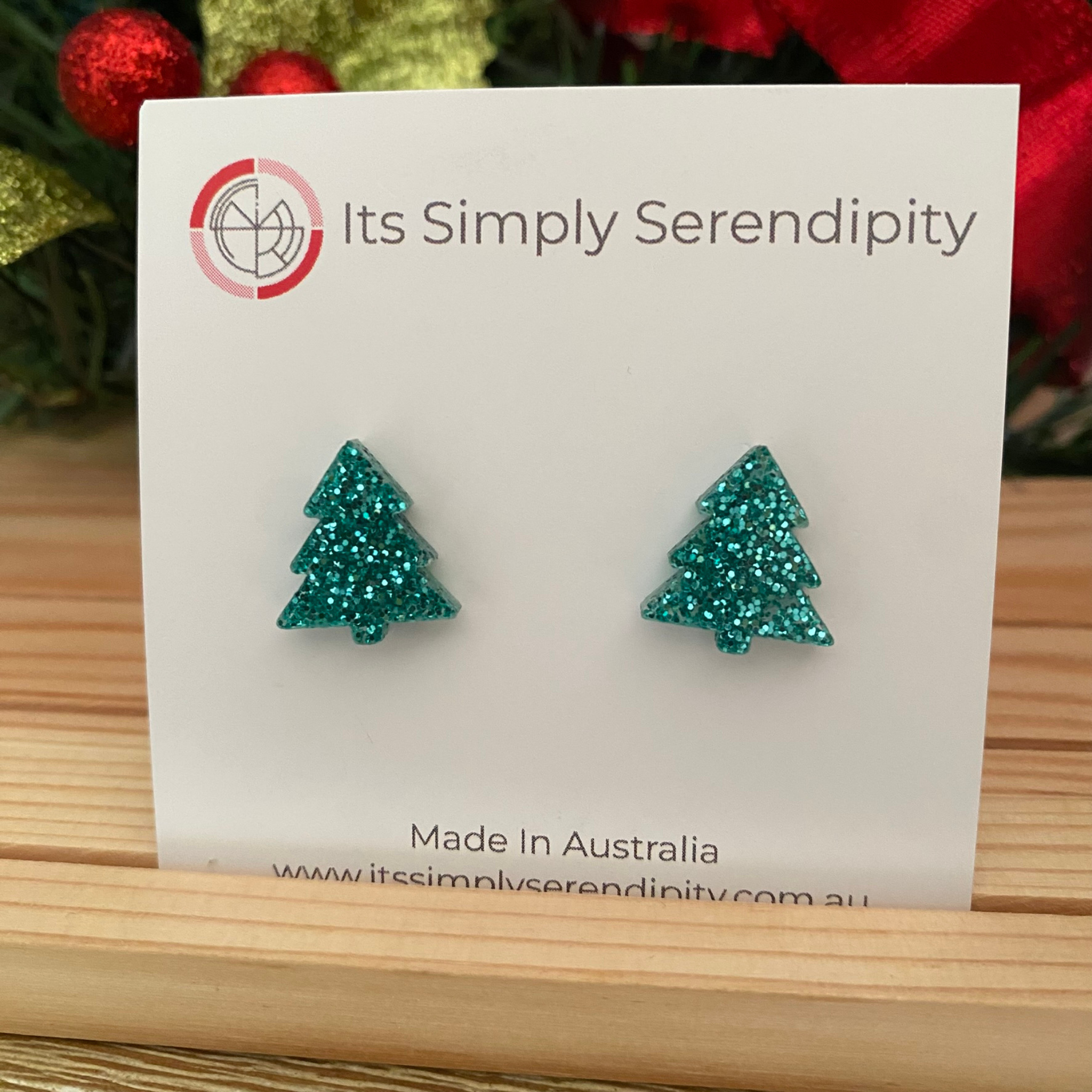 Aqua glittery tree-shaped earrings on a 'Its Simply Serendipity' card with a red glittery background.