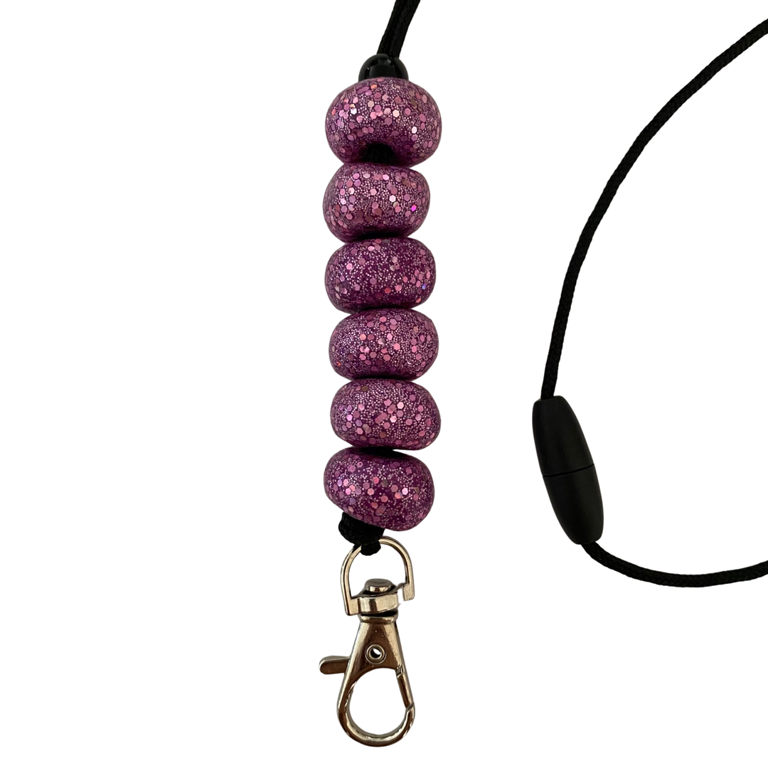 Handmade polymer clay lanyard with six hand-rolled beads in sparkly purples. Threaded on a nylon cord with a breakaway safety clasp and a silver-plated clip.