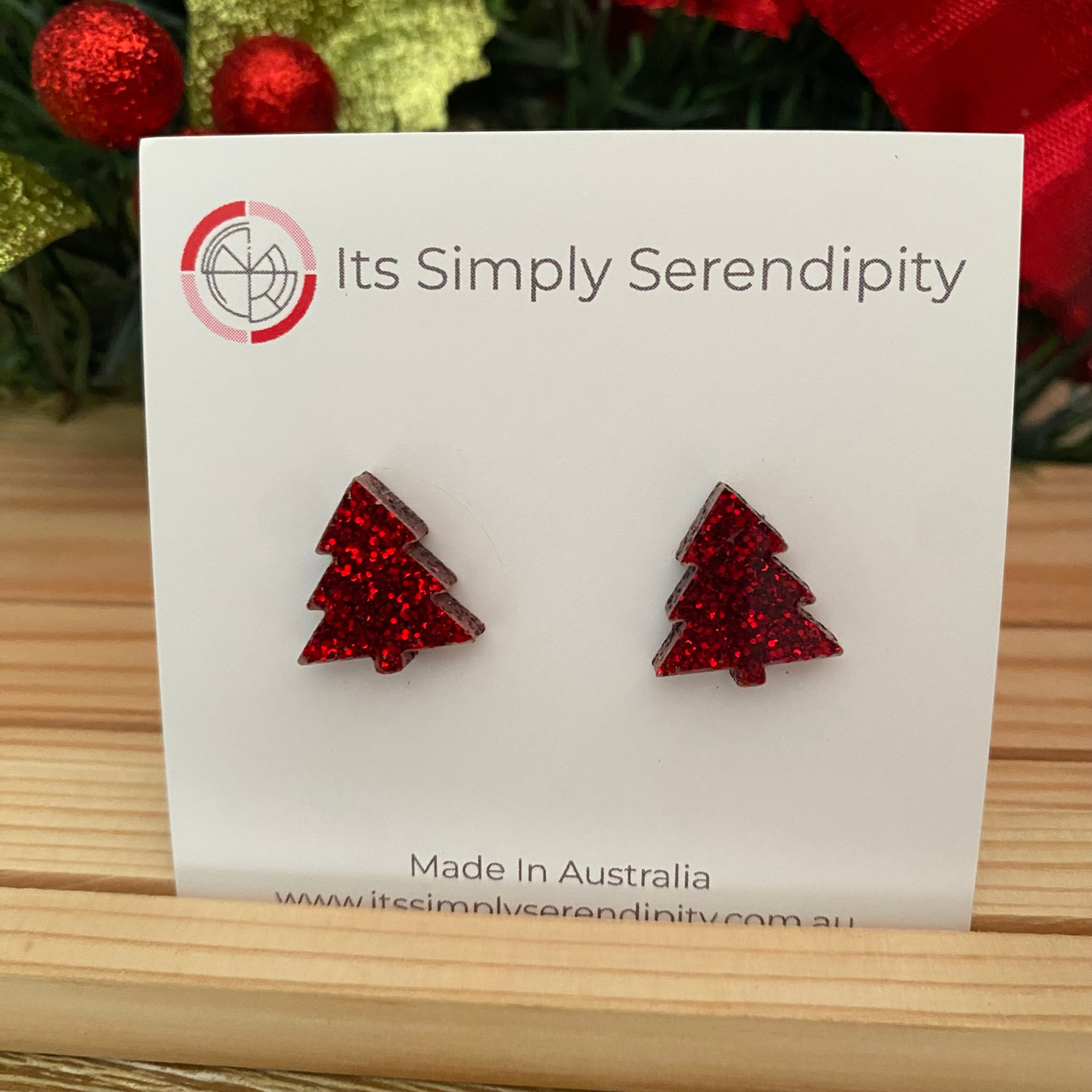 Red glittery Christmas tree earrings on a 'Its Simply Serendipity' card with a festive background.