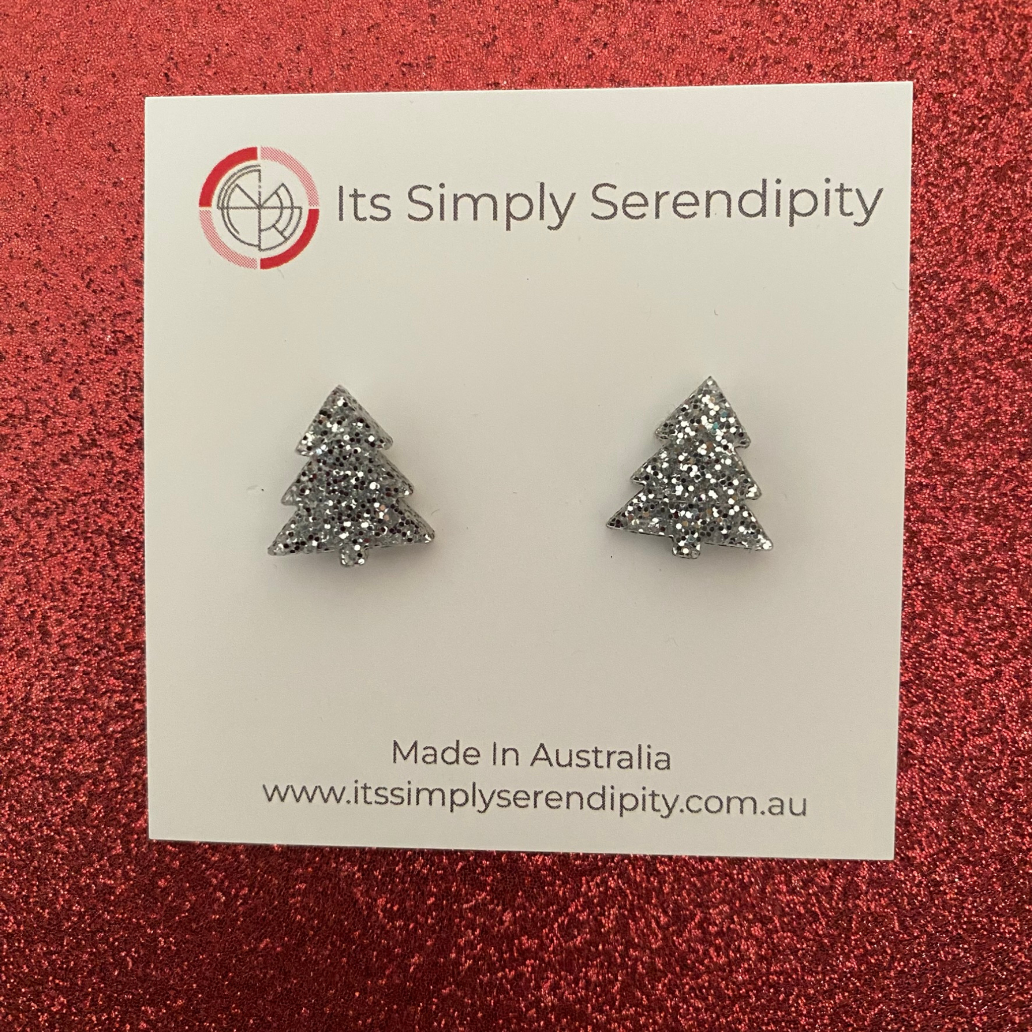 Silver tree-shaped earrings on a 'Its Simply Serendipity' card with a red background.