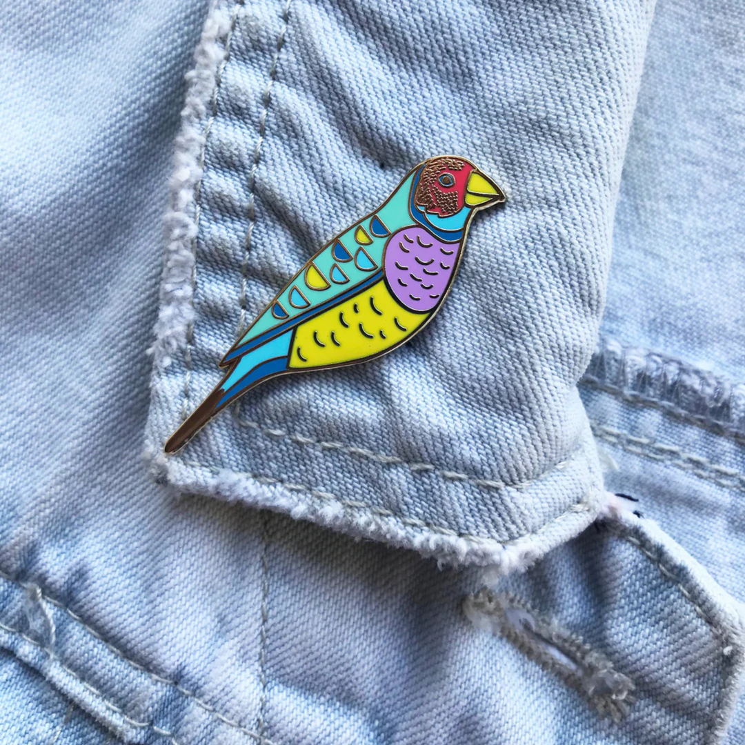 The Gouldian Finch Enamel Pin pictured on a denim jacket.