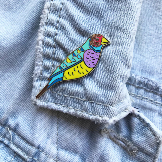 The Gouldian Finch Enamel Pin pictured on a denim jacket.
