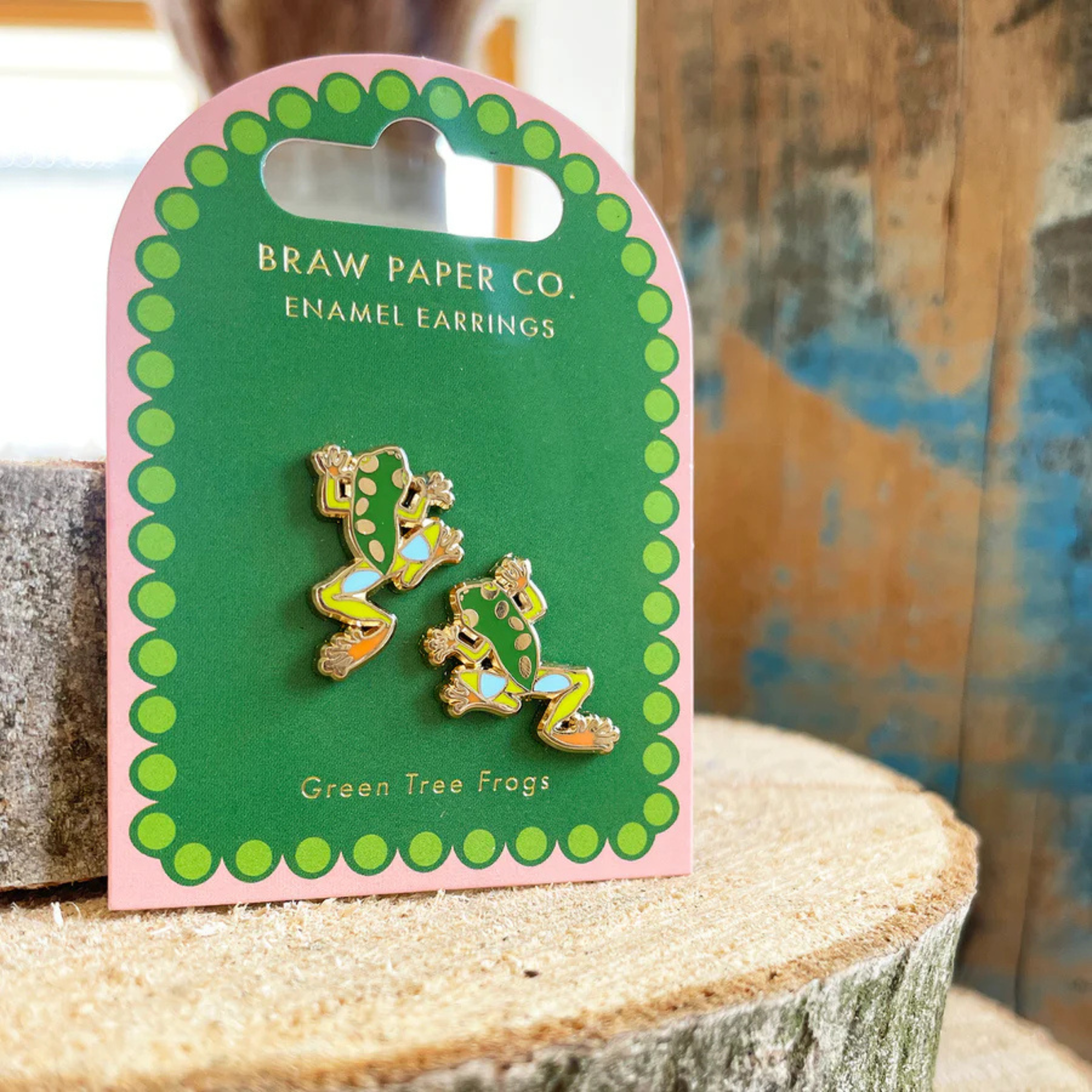 Enamel earrings of green tree frogs on a Braw Paper Co. card.