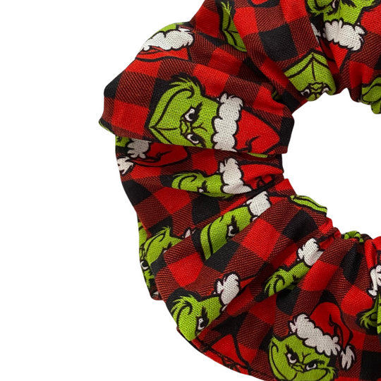 Scrunchie with Grinch pattern on a black and red check fabric on a white background.