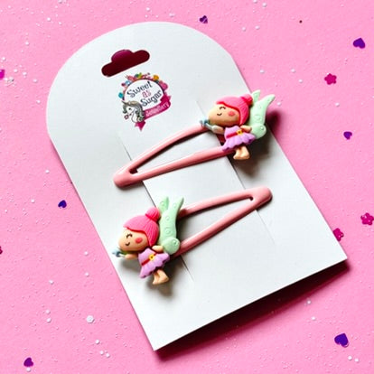 Two pink hair clips featuring a green winged fairy.
