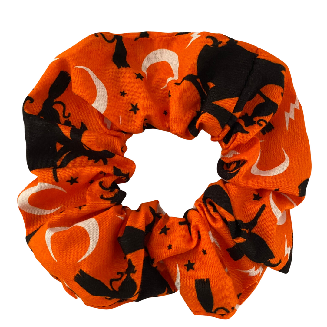 Halloween Scrunchie featuring black witches riding broomsticks on orange soft cotton woven fabric.