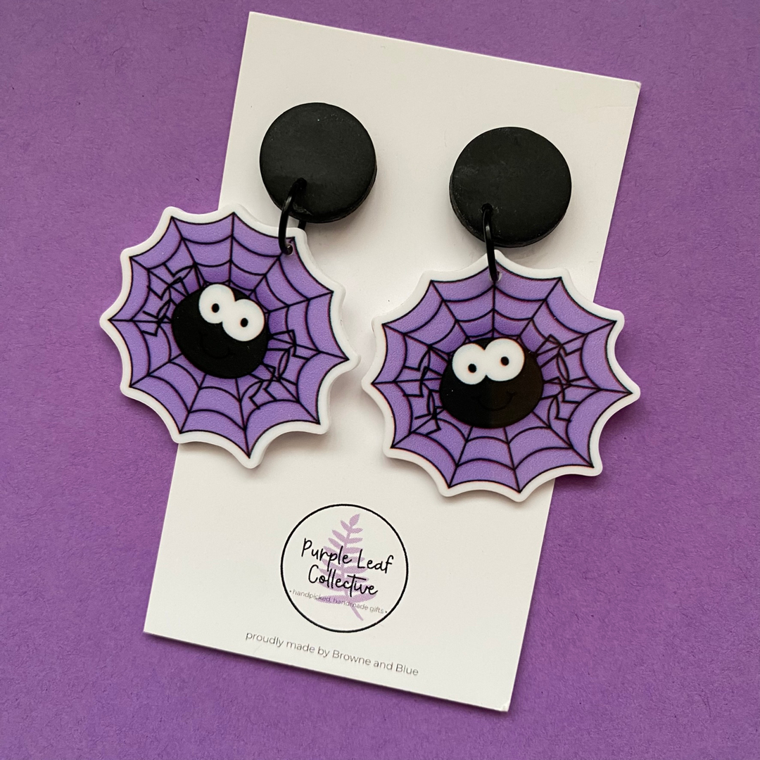 Spider web earrings on a card with 'Purple Leaf Collective' branding against a purple background.