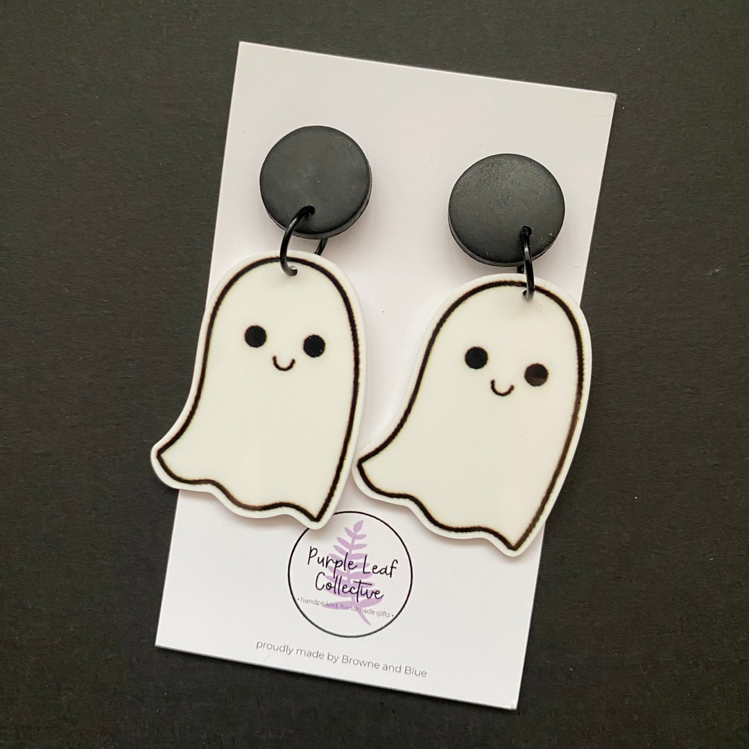 Ghost-shaped earrings on a card with 'Purple Leaf Collective' branding against a dark background.