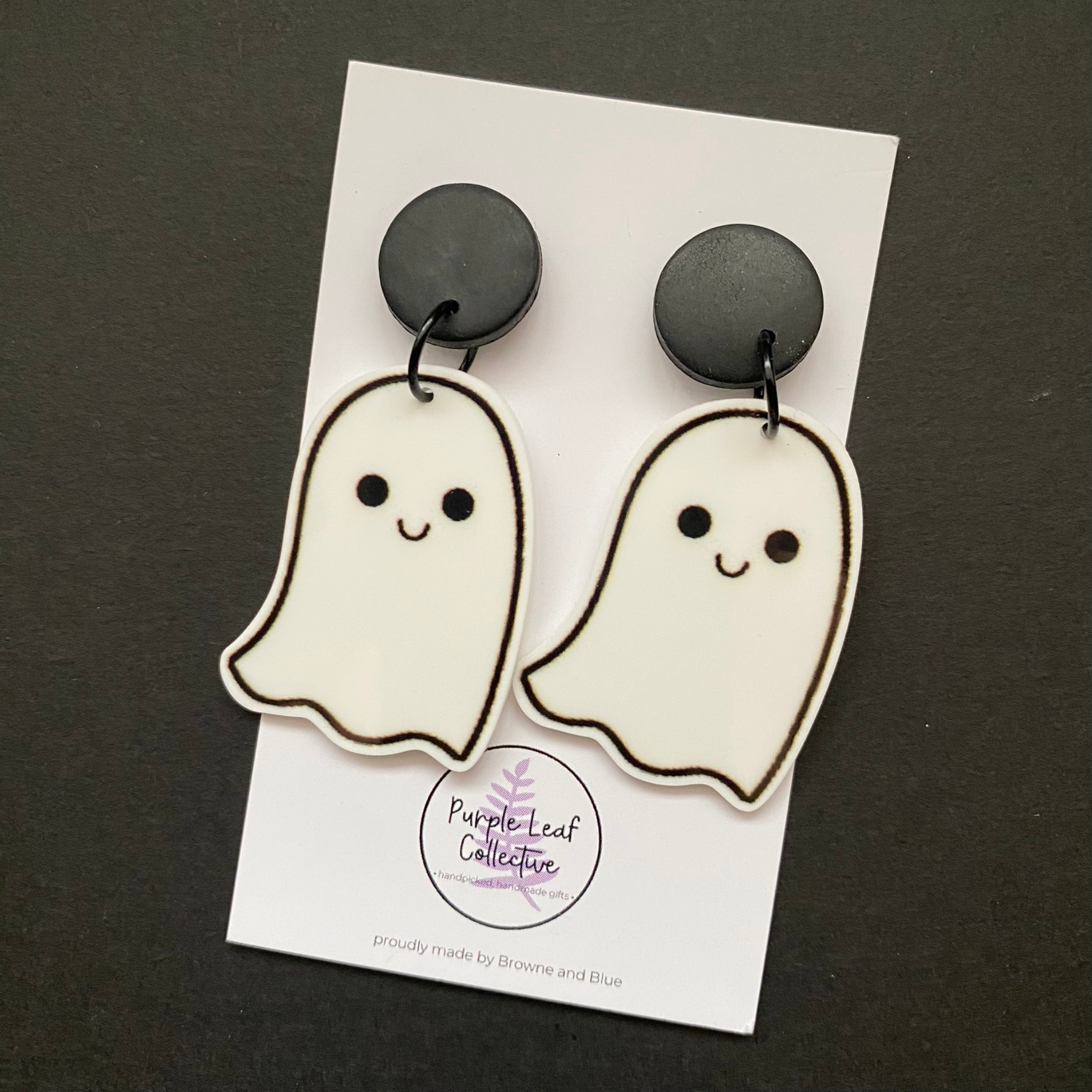 Ghost-shaped earrings on a card with 'Purple Leaf Collective' branding against a dark background.