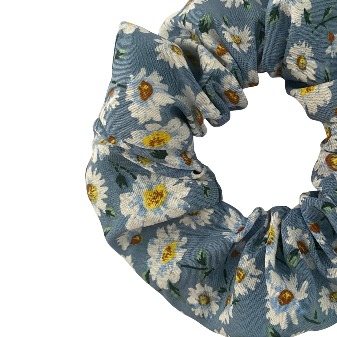 A scrunchie with white daisies on a rich blue fabric.