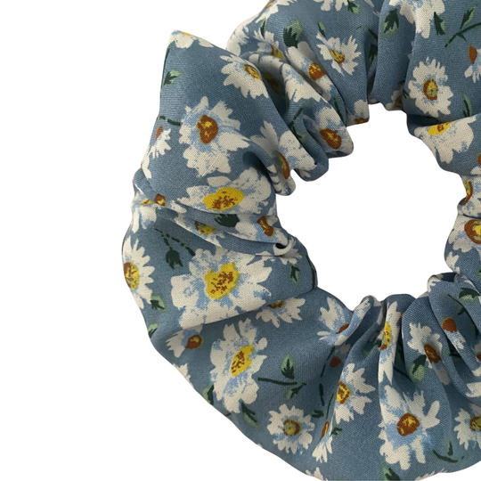 A scrunchie with white daisies on a rich blue fabric.