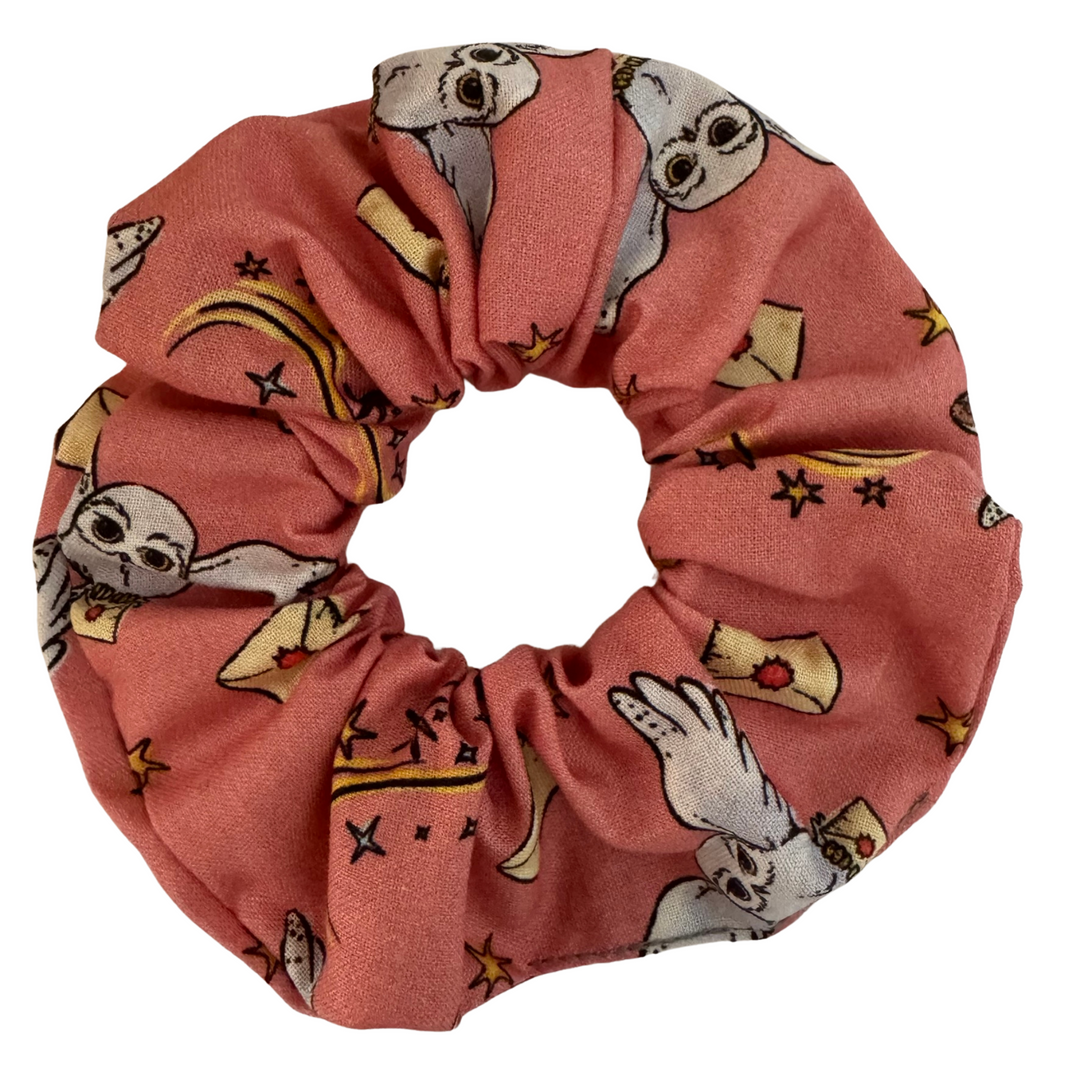 Harry Potter Hedwig Scrunchie featuring a images of Hedwig the owl against on a peach fabric.