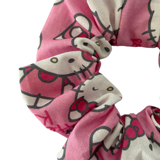 Pink scrunchie with cat pattern on a white background.