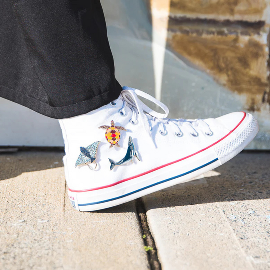 A picture of the Humpback Whale, Sea Turtle and Eagle Ray Enamel Pins pinned on a shoe.