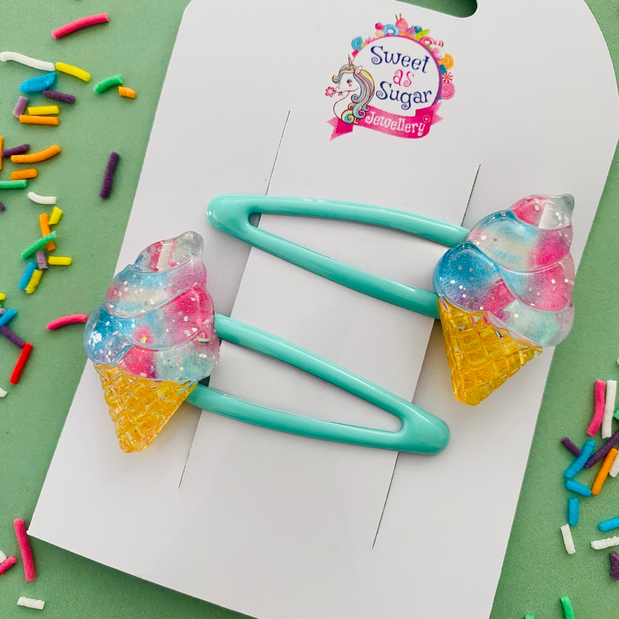 A pair of aqua blue snap clips featuring colourful ice cream with a golden cone.