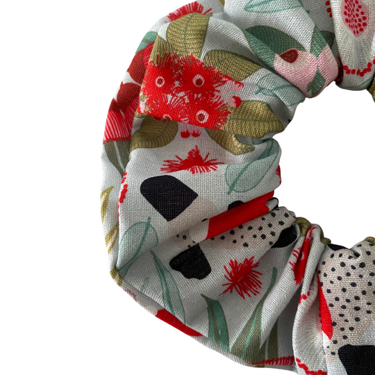 A silver fabric scrunchie featuring festive images of aussie animals and native flora.