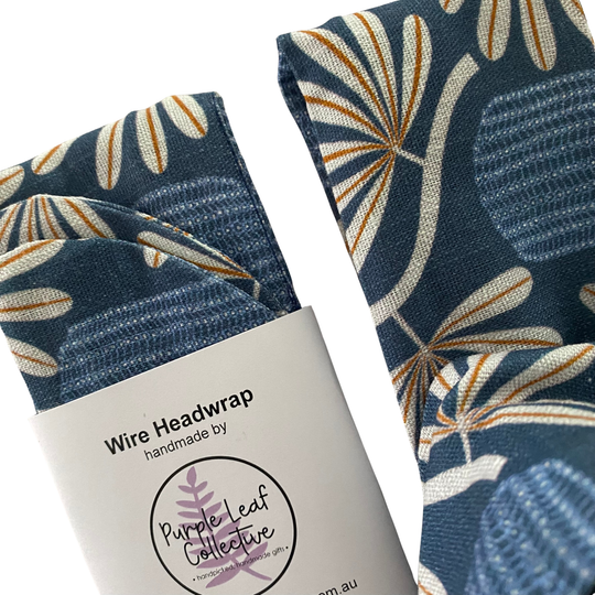 Close up view of a wire headwrap features a banksia plant repeat pattern on a royal blue backdrop.