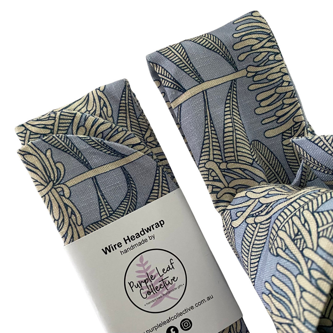Close up view of a wire headwrap featuring a bone waratah repeat pattern on a soft blue-grey backdrop.