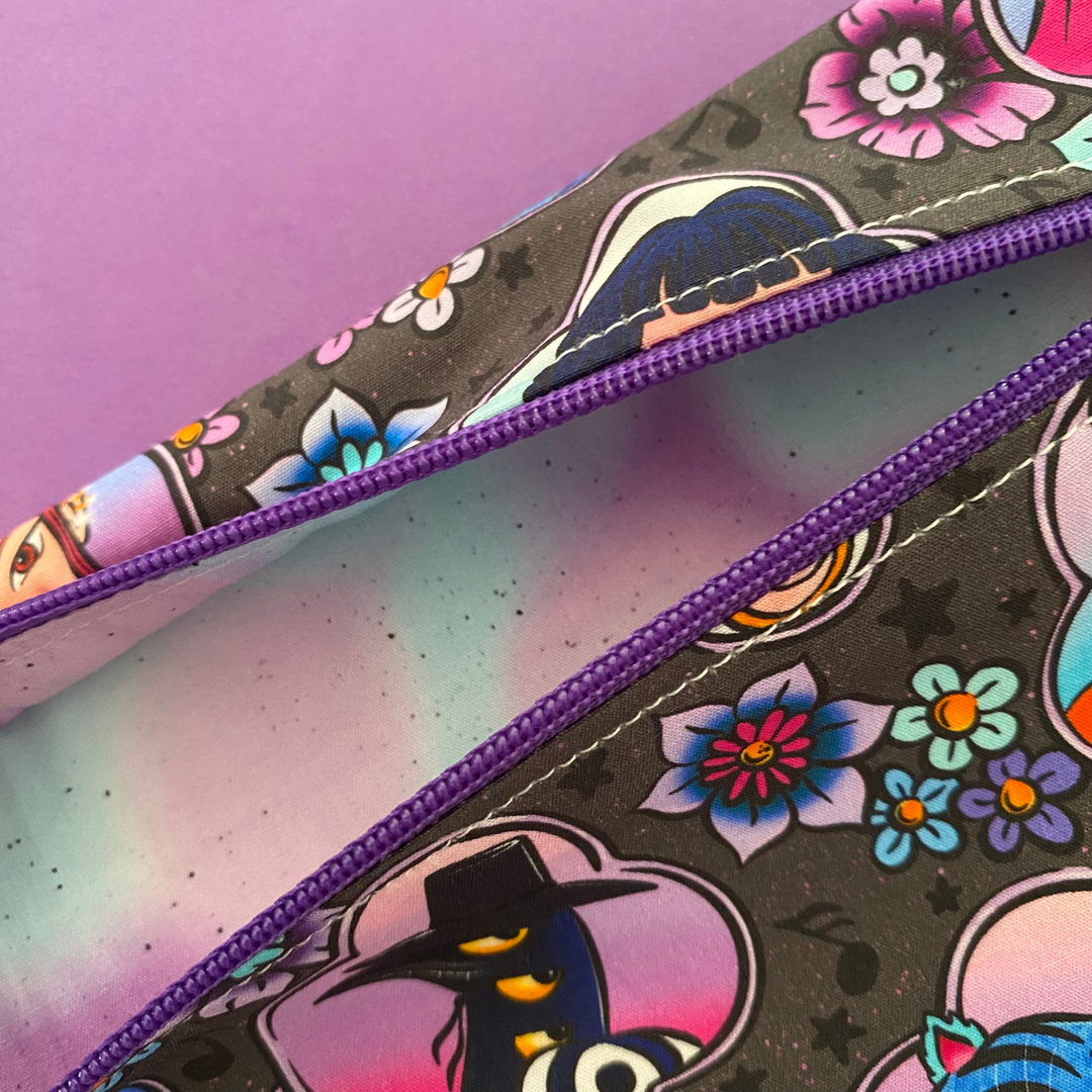 Lining view of colourful pencil case with floral and witch designs on a purple background.