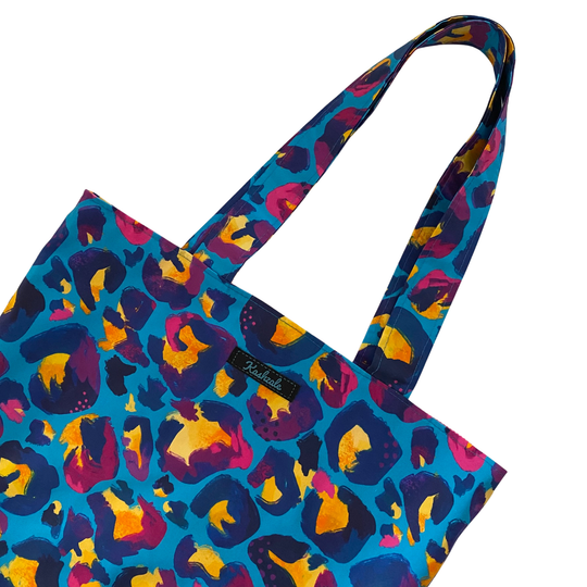 Colourful blue leopard print tote bag with a visible brand logo on a white background.